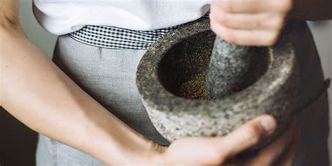 woman using mortar and pestle to process dried herbs